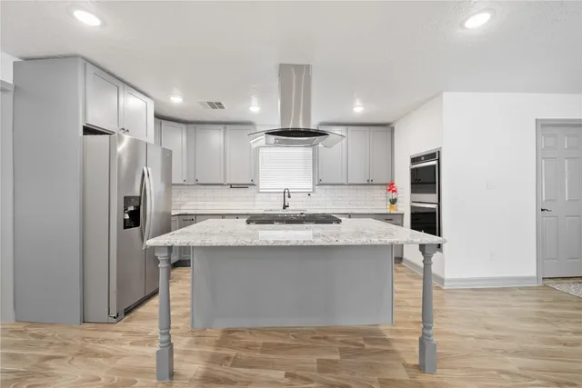 a kitchen with kitchen island a sink stainless steel appliances and refrigerator