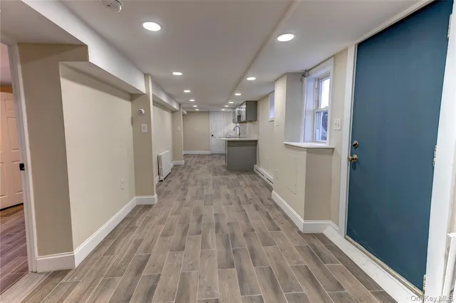 a view of a hallway with wooden floor and a bathroom