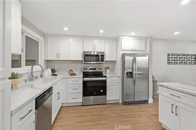 a kitchen with white cabinets and wooden floors
