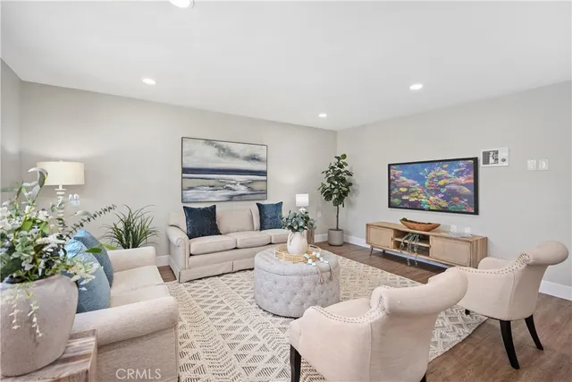 a living room with furniture a potted plant and kitchen view