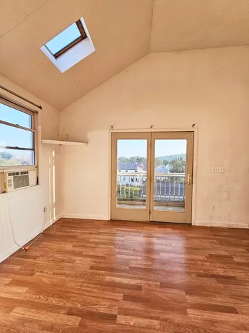 a view of an empty room with a window and wooden floor