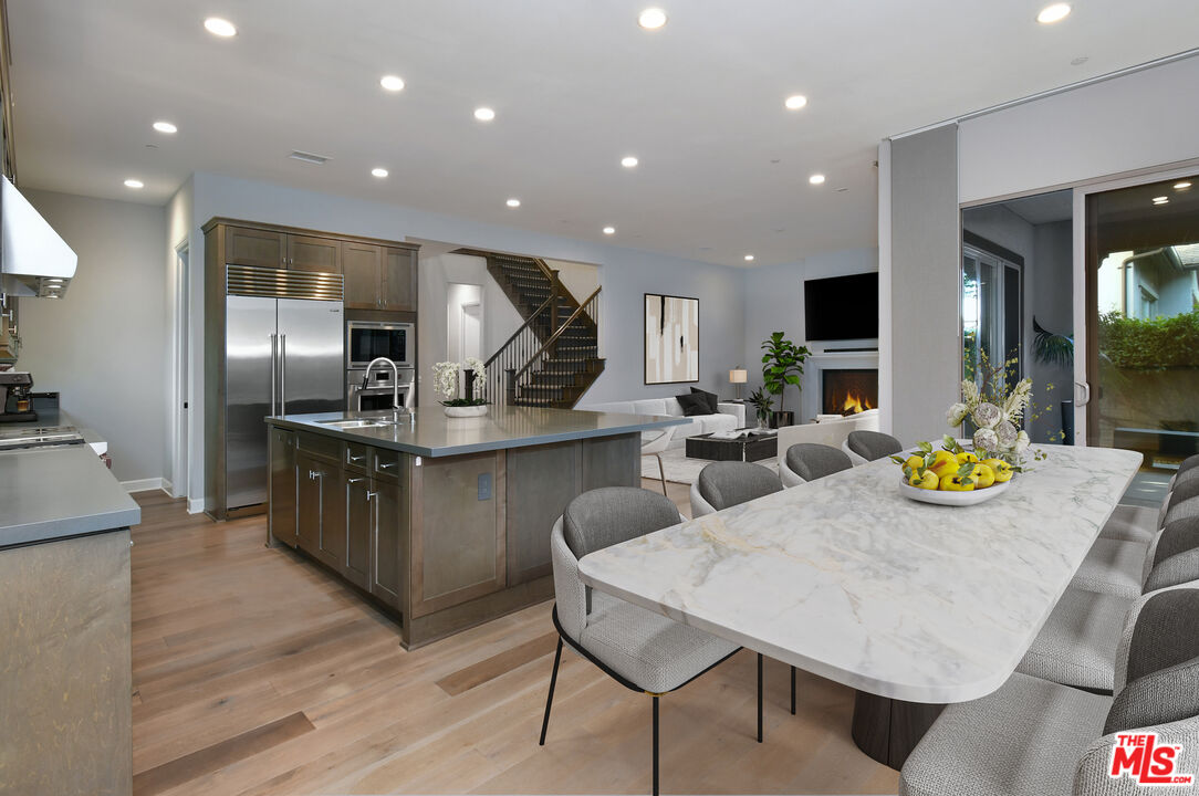 14608 McCormick Street Sherman Oaks, CA 91411 - Photo 8 of 29 a kitchen with stainless steel appliances kitchen island granite countertop a table chairs sink and wooden floor