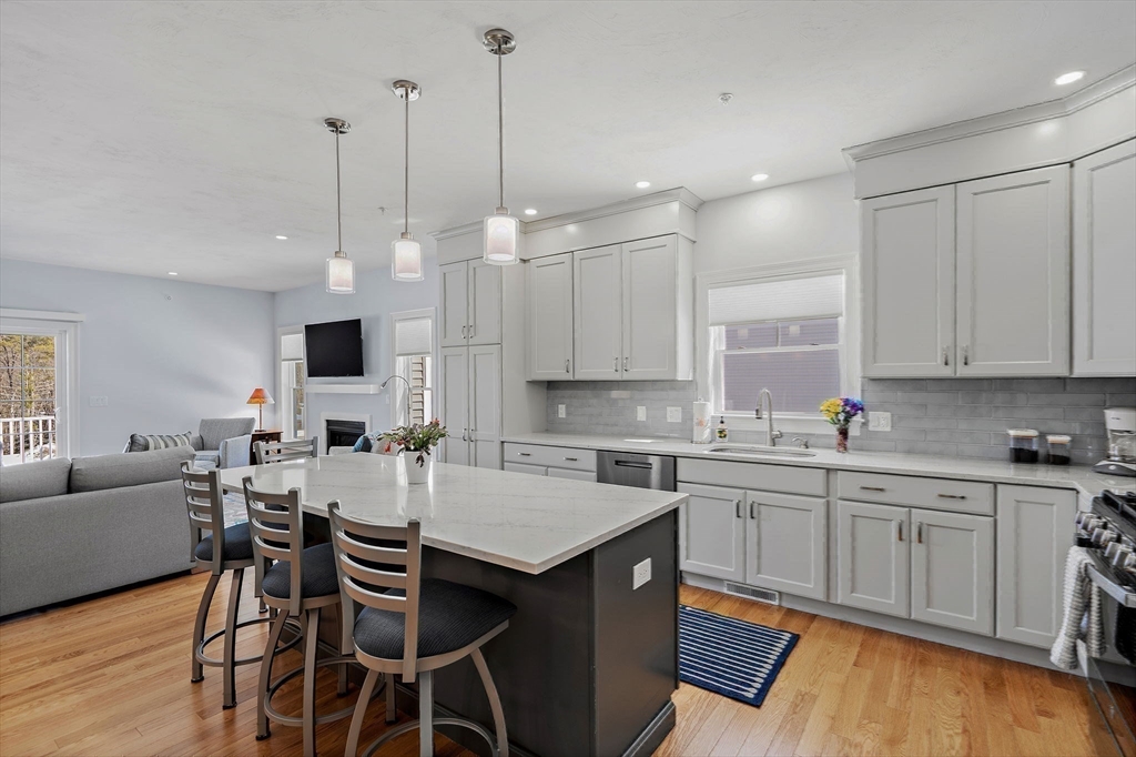 6 Chickadee Way, Unit 23 Upton, MA 01568 - Photo 16 of 41 a kitchen with stainless steel appliances kitchen island granite countertop a sink a stove a dining table and chairs