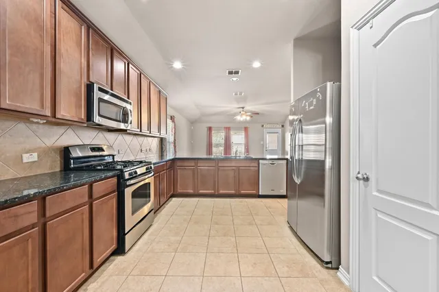 a view of a refrigerator in kitchen and an empty room and a kitchen