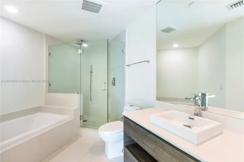 a bathroom with a sink a toilet a mirror a bathtub and shower