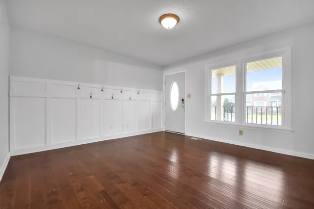 an empty room with wooden floor and windows