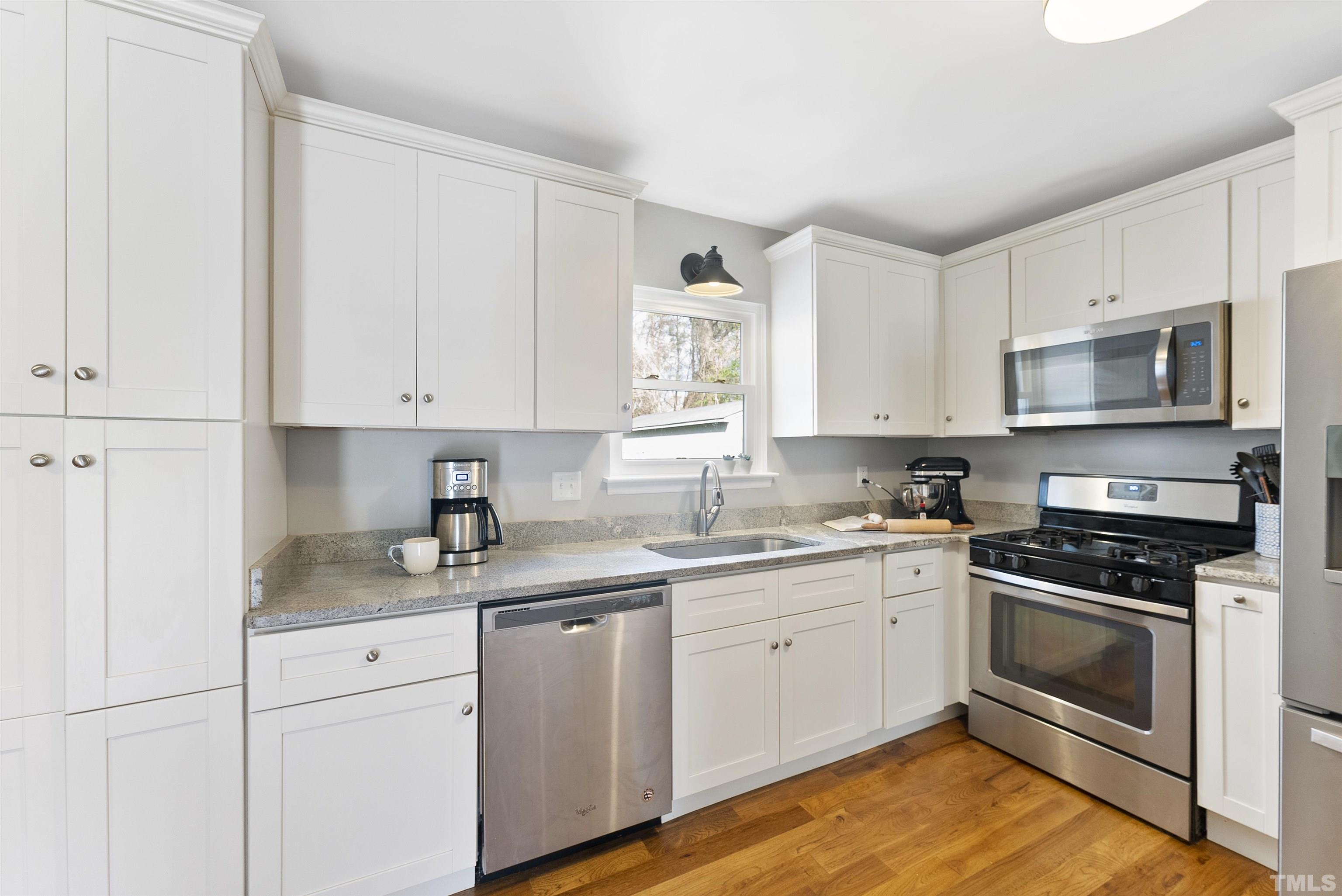 5413 Old Towne Road Raleigh, NC 27612 - Photo 14 of 34 a kitchen with cabinets stainless steel appliances a sink and wooden floor