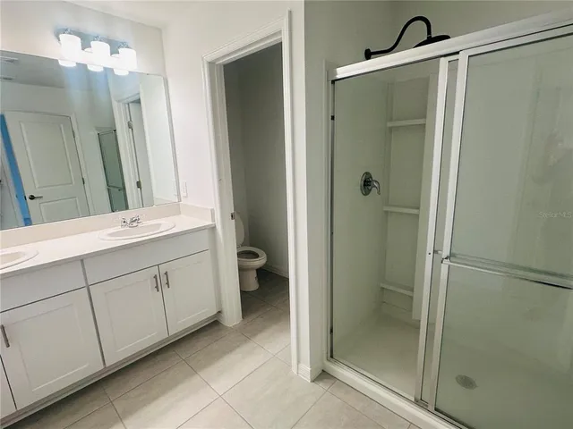 a bathroom with a double vanity sink mirror and shower