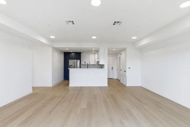 a view of kitchen with kitchen island wooden floor center island and stainless steel appliances