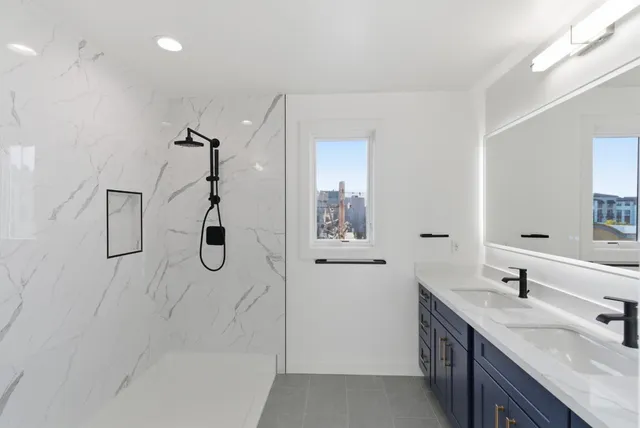 a bathroom with a double vanity sink a toilet a window and mirror