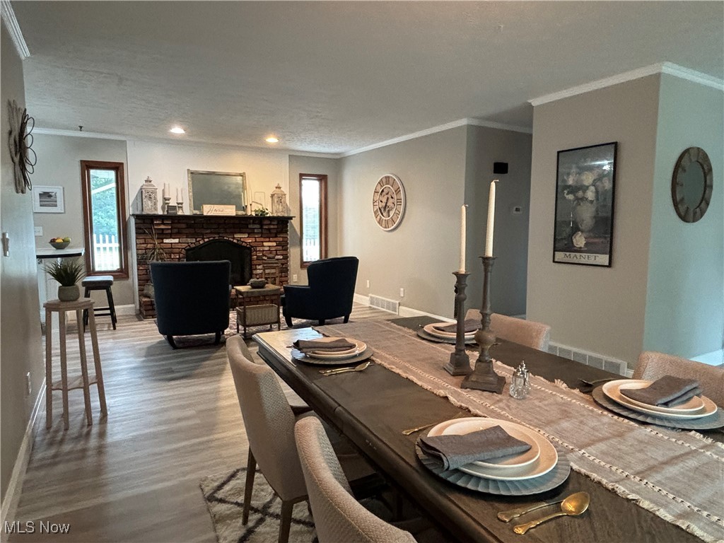 5418 River Road Madison, OH 44057 - Photo 24 of 43 Dining room featuring a fireplace, a textured ceiling, ornamental molding, and hardwood / wood-style flooring