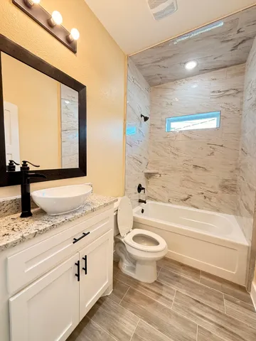 a bathroom with a granite countertop toilet a sink and a bathtub