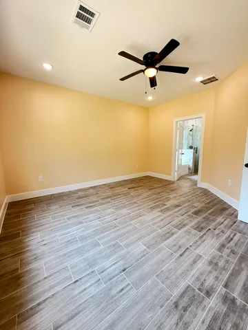 an empty room with wooden floor and windows