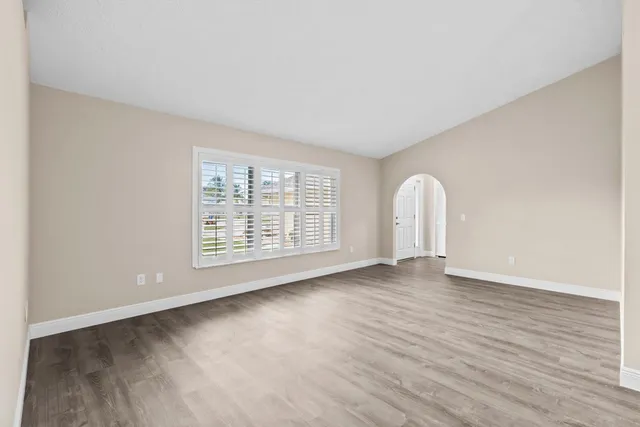 a view of an empty room with wooden floor and a window