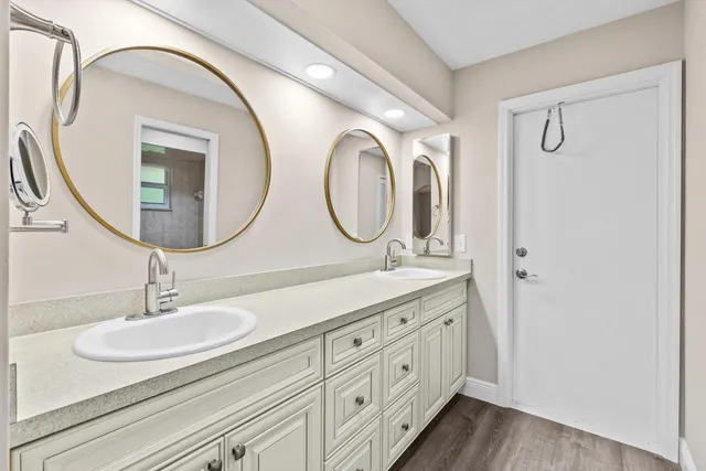 a bathroom with a granite countertop double vanity sink and a mirror