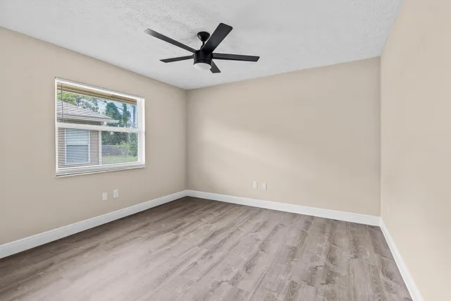 a view of empty room with wooden floor and fan