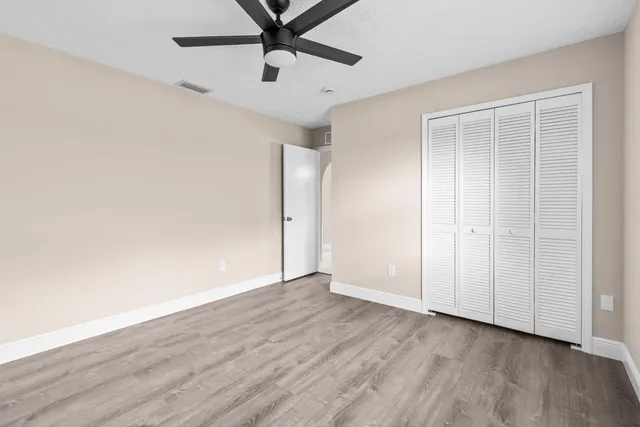 an empty room with wooden floor closet and windows