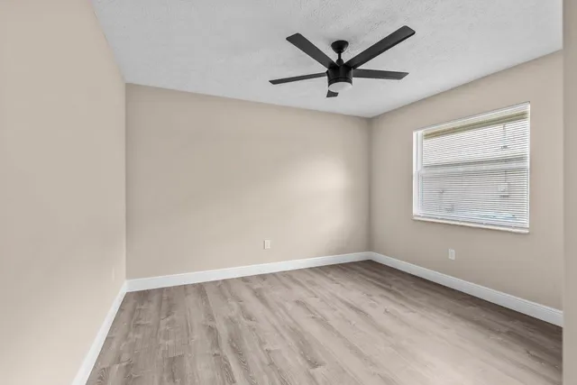 an empty room with a window and a ceiling fan