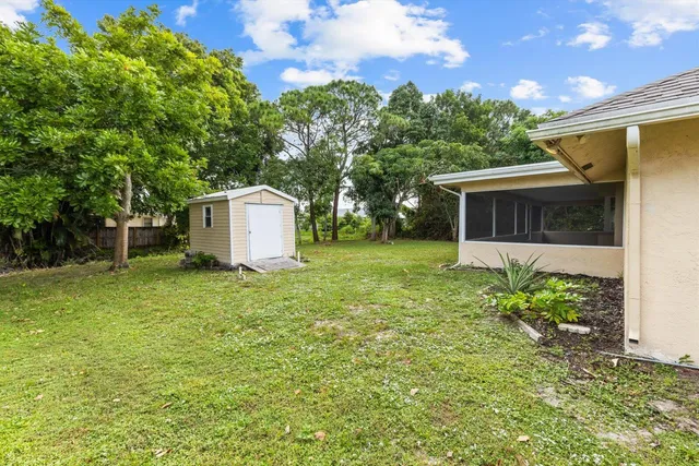 a backyard of a house with plants and large tree