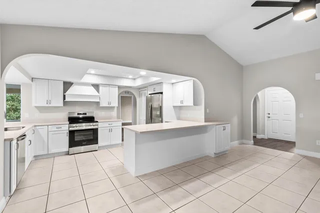 a large white kitchen with a stove a sink dishwasher and a oven