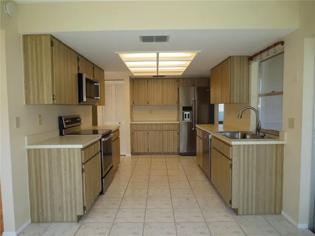 a kitchen with stainless steel appliances granite countertop a stove top oven a sink and a refrigerator