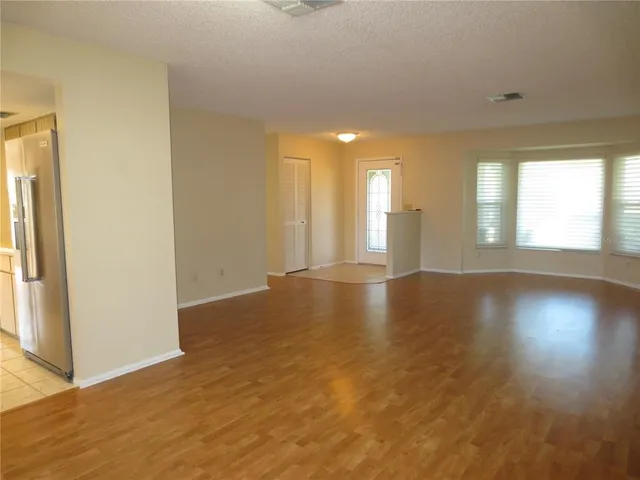 an empty room with wooden floor and windows with curtains