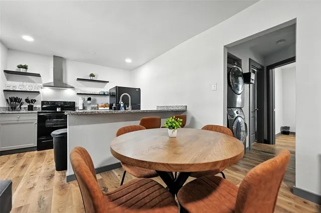 a kitchen with stainless steel appliances granite countertop a dining table chairs and a refrigerator