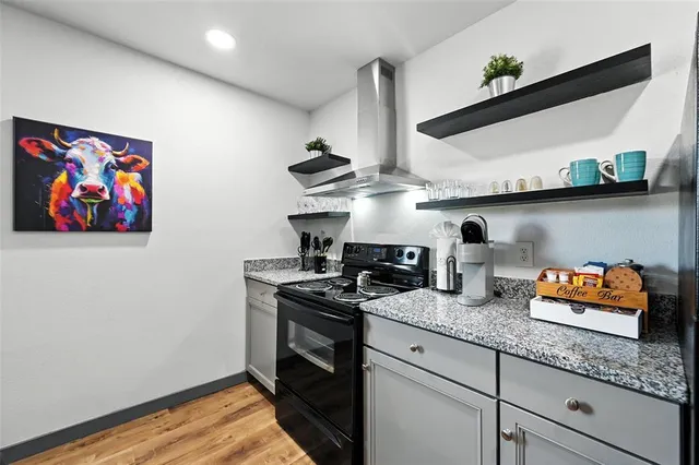 a kitchen with stainless steel appliances granite countertop a sink a stove and wooden floor