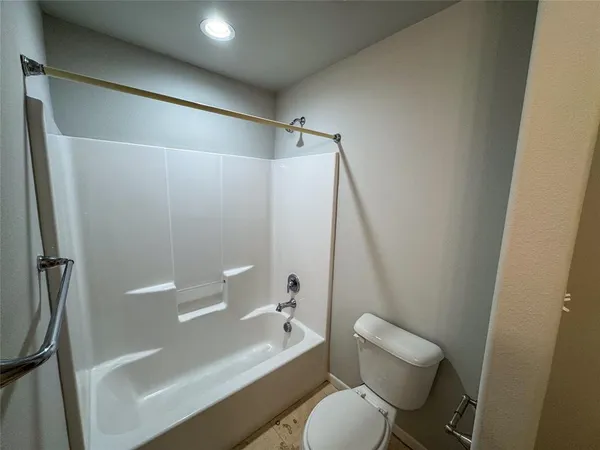 a white toilet sitting next to a bath tub