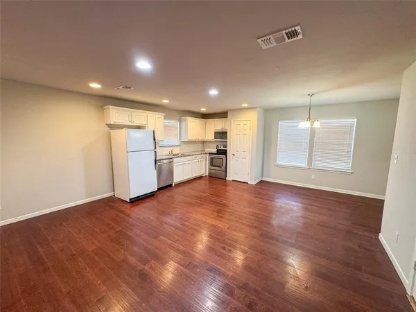 a view of a kitchen with refrigerator and wooden floor