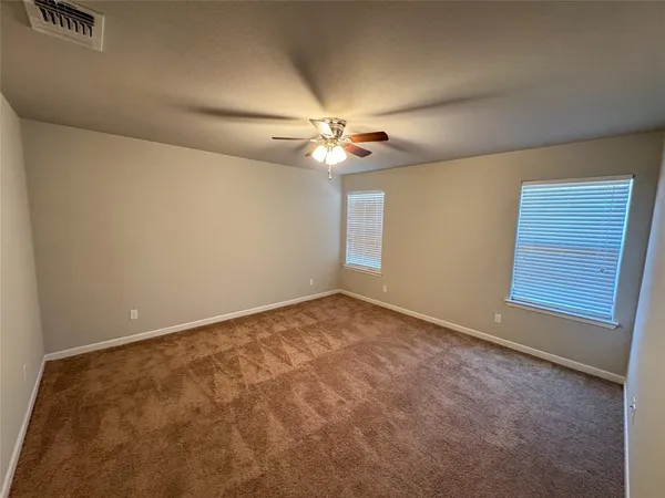 an empty room with windows and ceiling fan
