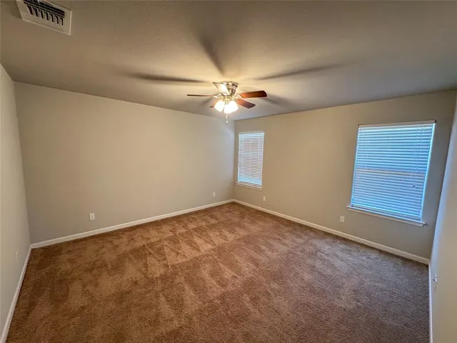 an empty room with windows and ceiling fan