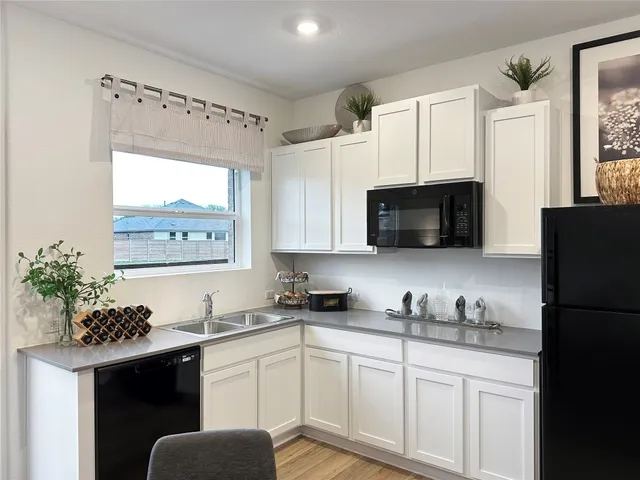 a kitchen with granite countertop white cabinets and black appliances