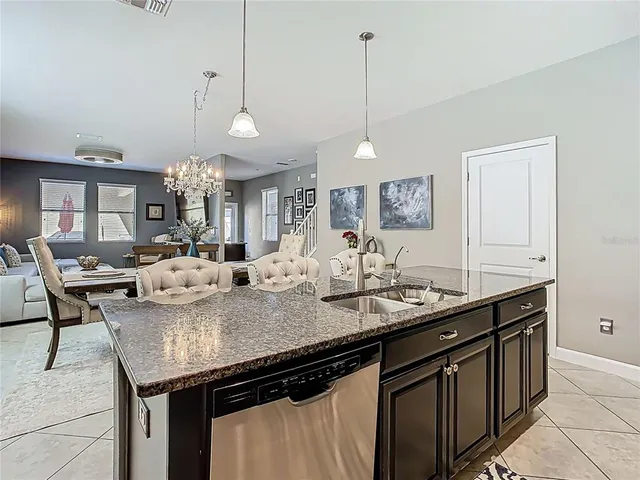 a kitchen with granite countertop cabinets a sink and a chandelier