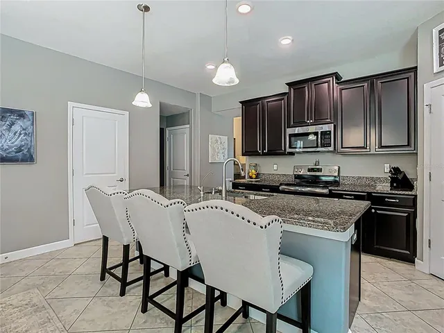 a kitchen with stainless steel appliances granite countertop a stove a sink a microwave a island with a dining table and chairs