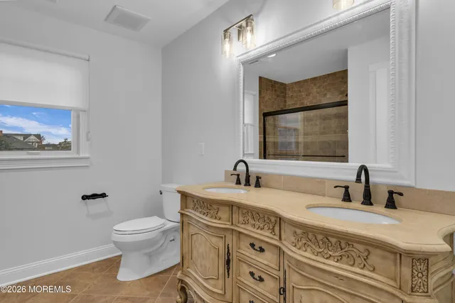 a bathroom with a granite countertop double vanity sink a mirror and a toilet