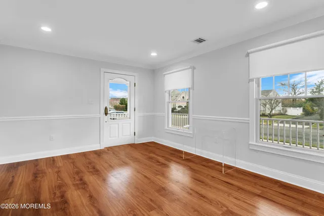 a view of an empty room with a window and wooden floor