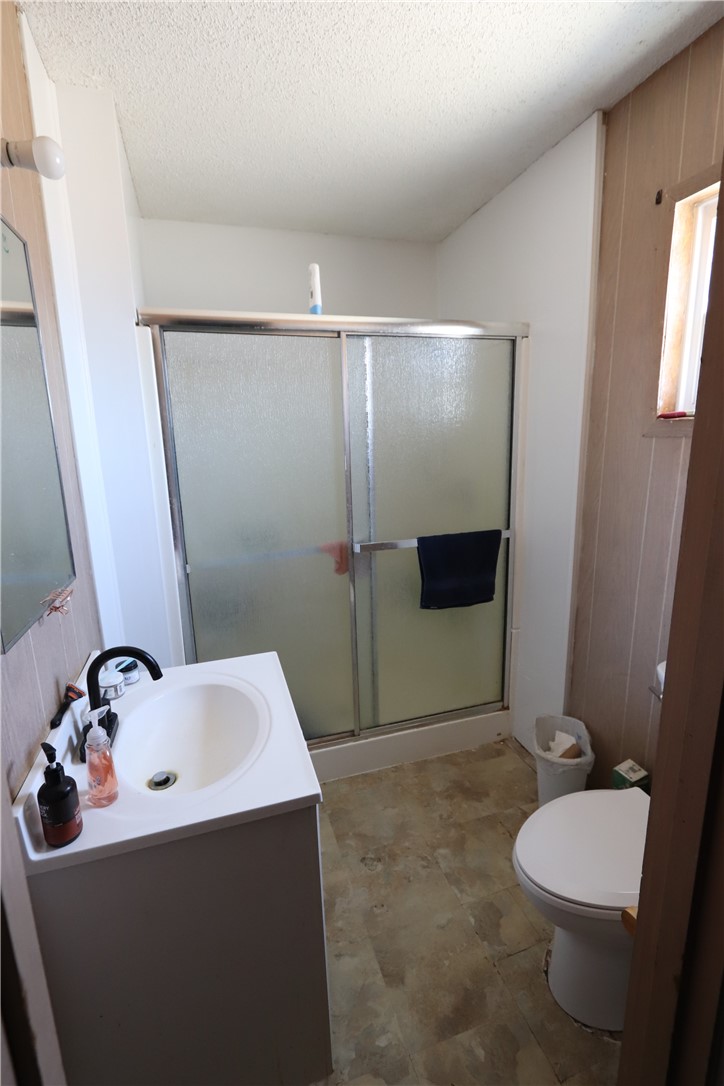 1290 Hammer Road Fort Mohave, AZ 86426 - Photo 14 of 16 Primary bathroom featuring a white vanity with integrated sink, matte black faucet, and a shower with frosted sliding glass doors.