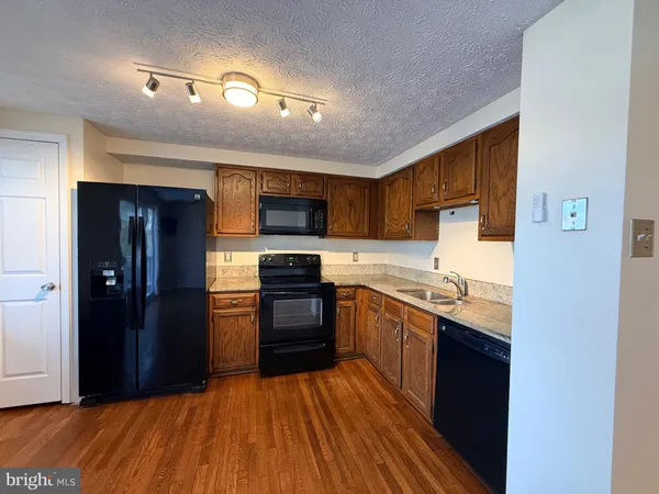 a kitchen with granite countertop a stove top oven and refrigerator