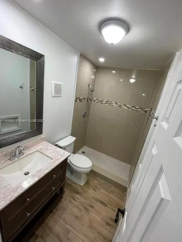 a bathroom with a sink a toilet a mirror and shower
