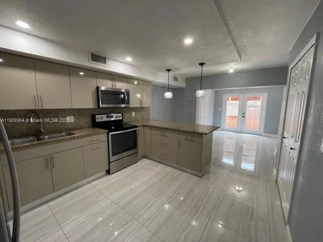 a large kitchen with stainless steel appliances kitchen island granite countertop a sink and cabinets