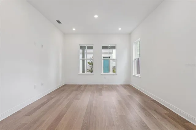 an empty room with wooden floor and windows