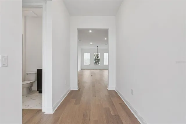 a view of a hallway with wooden floor and a bathroom