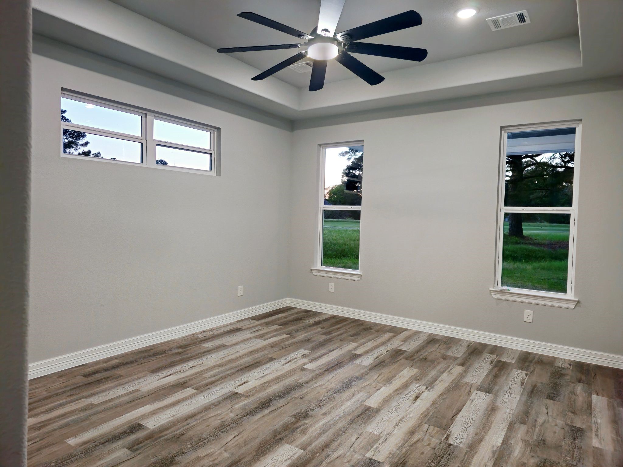 20 Lazy Springs Trinity, TX 75862 - Photo 23 of 37 Primary bedroom with tray ceilings and large windows and, a modern ceiling fan.