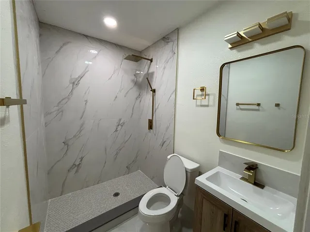 a bathroom with a granite countertop sink toilet a mirror and shower