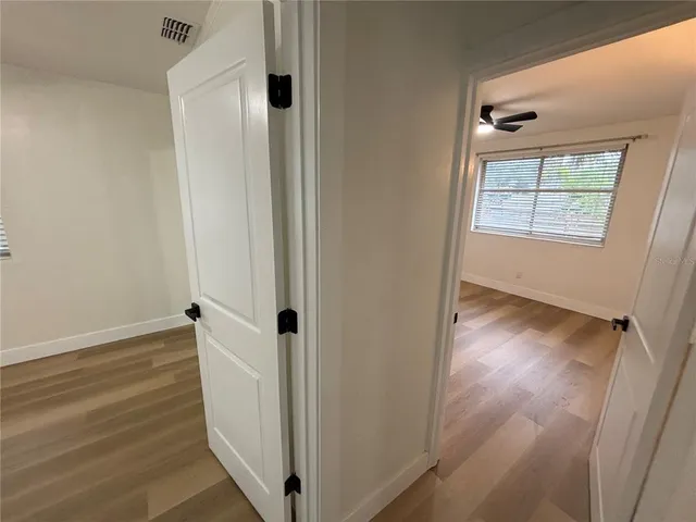 an empty room with wooden floor cabinet and windows