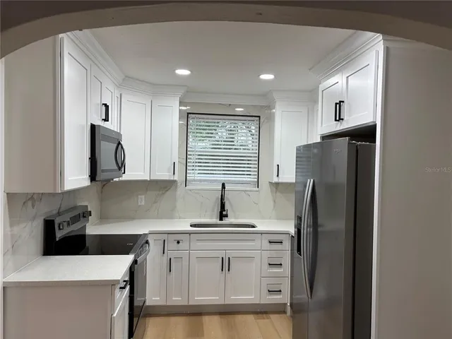 a kitchen with stainless steel appliances granite countertop a refrigerator sink and stove