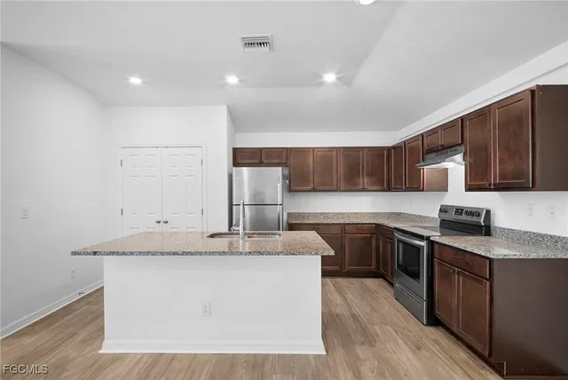a kitchen with stainless steel appliances granite countertop a sink stove and refrigerator