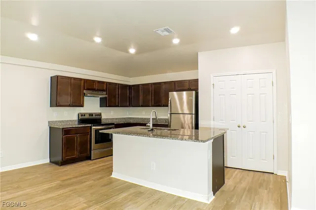 a kitchen with stainless steel appliances a stove top oven a sink a refrigerator and a window