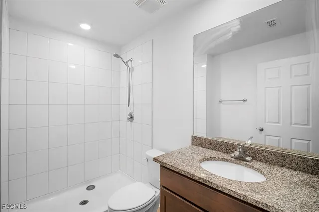 a bathroom with a granite countertop sink a toilet a mirror and shower